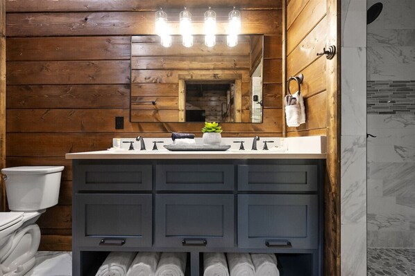A bathroom with wooden walls, a white sink, and a mirror above the vanity.