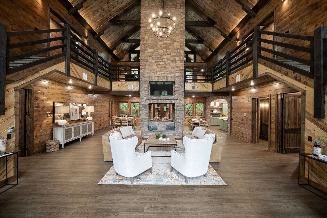 A spacious living area with a stone fireplace, wooden beams, and a high ceiling.