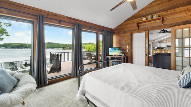 A bedroom with a large window, a bed, a chair, and a desk. - Crystal Springs - Lakefront with Hot Tub! (Linn Creek)