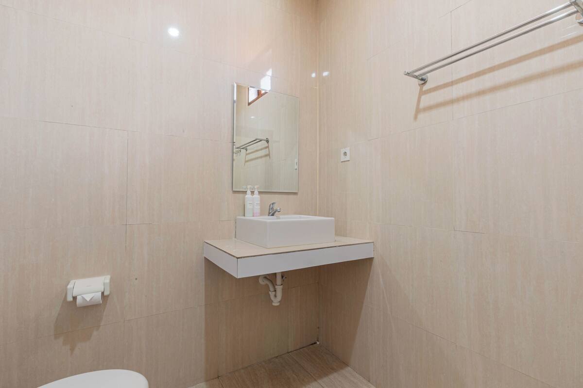 A modern bathroom with a white sink, mirror, and towel rack.