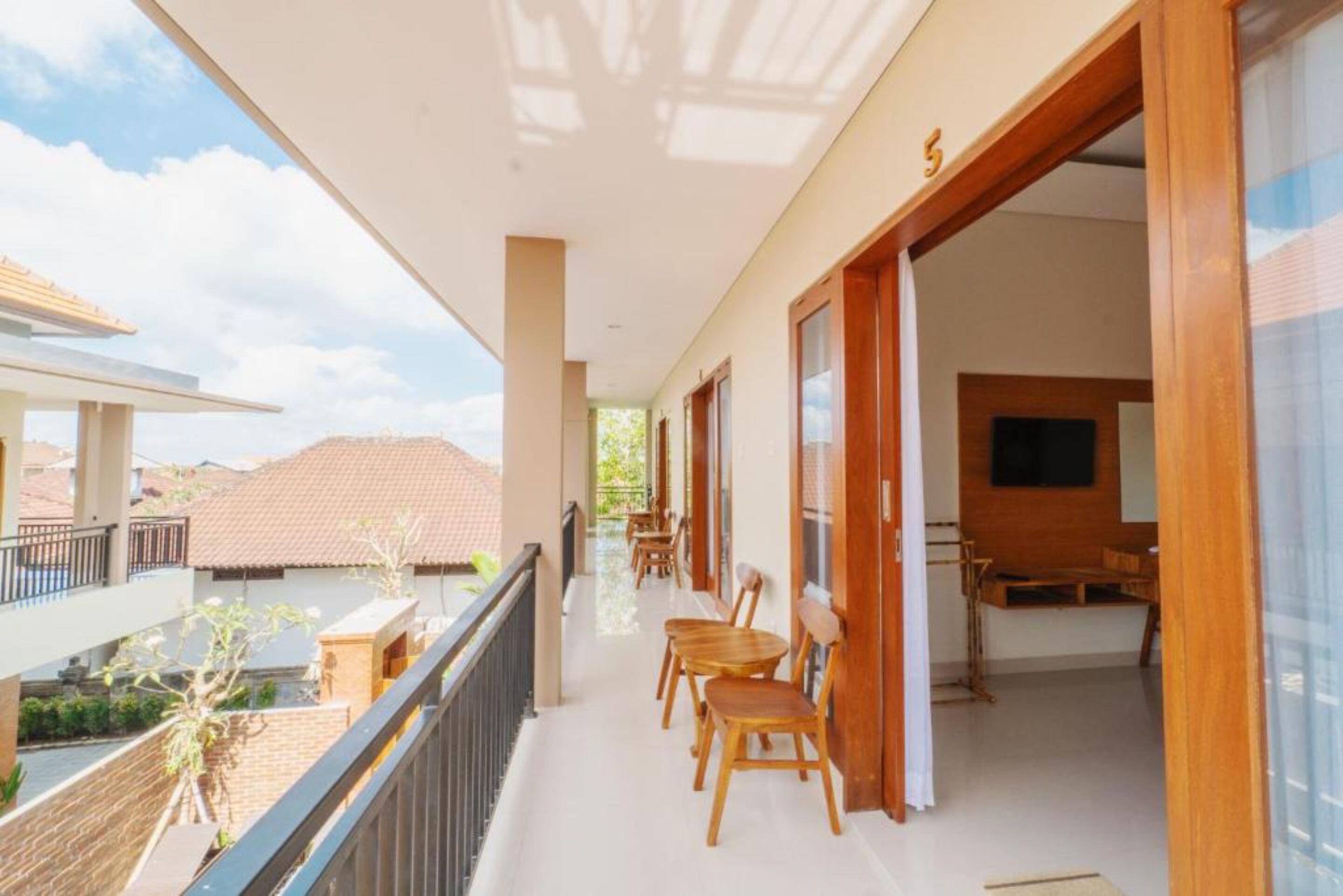 A hotel corridor with wooden chairs, a balcony, and a view of the cityscape.
