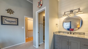 Un bagno con un mobile lavabo, uno specchio rotondo e una citazione incorniciata al muro.