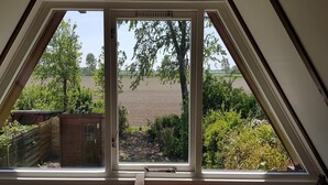 A room with a skylight window overlooking a garden and a field.