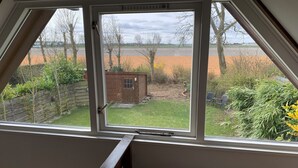 A room with a large window overlooking a garden and a field.