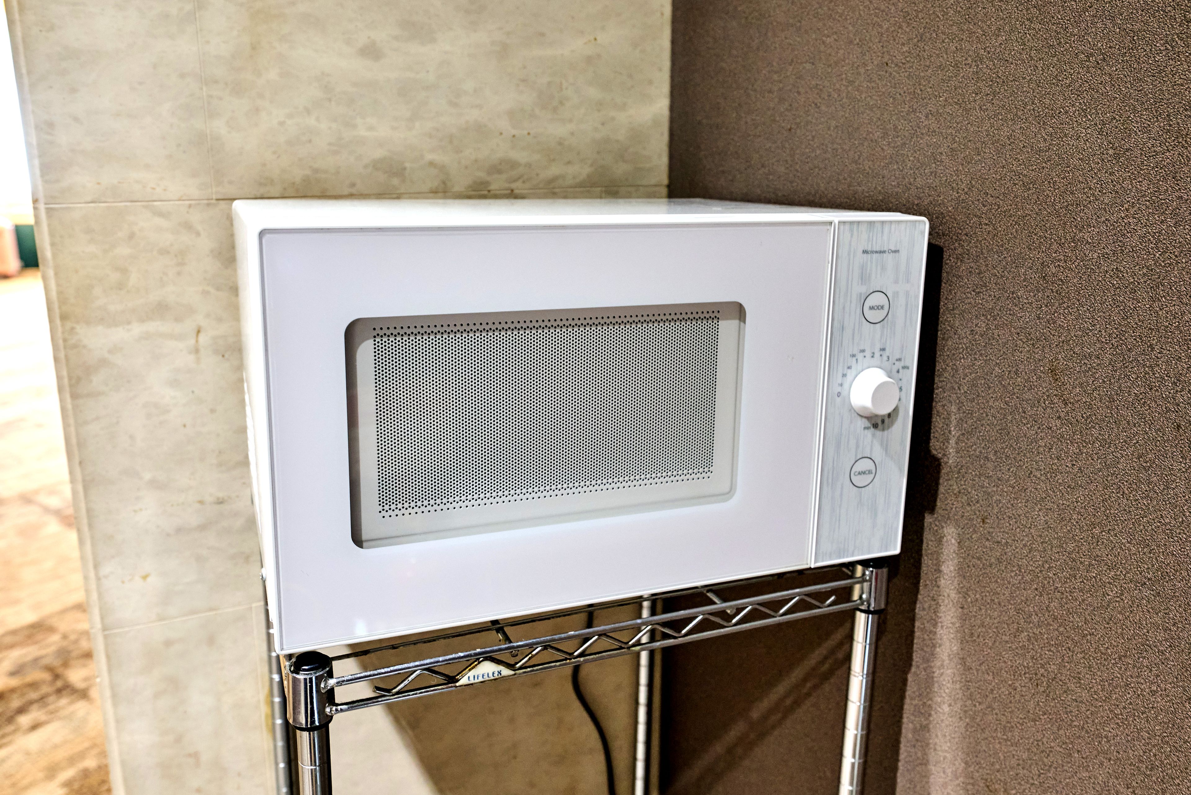 A microwave oven mounted on a metal stand with a control panel on the right side.