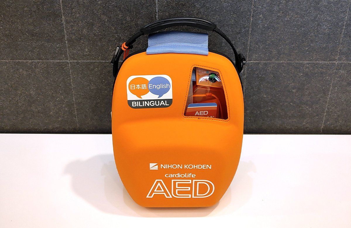 Uma bolsa de DEA laranja com etiquetas bilíngues e uma alça azul.