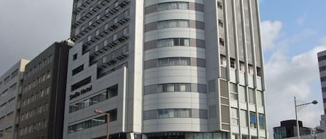 A modern hotel with a curved facade, multiple floors, and a prominent 'Smile Hotel' sign.