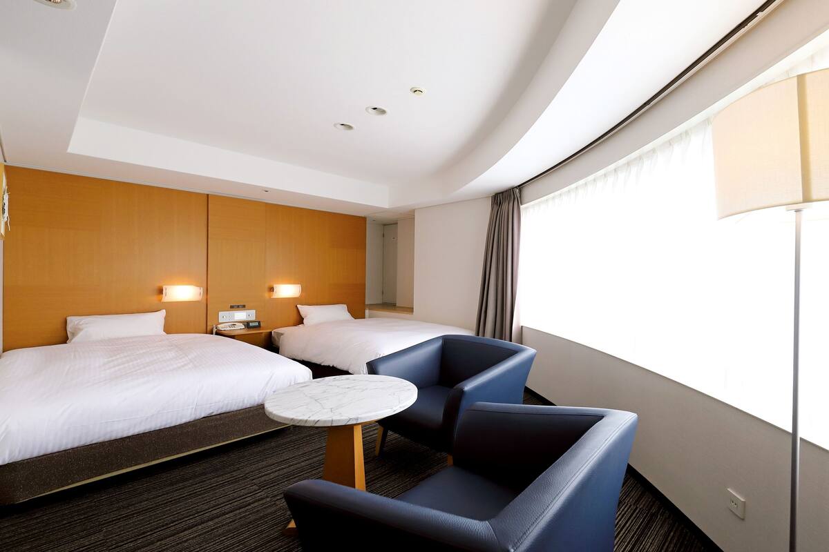 Une chambre d’hôtel avec deux lits, une petite table et une chaise.