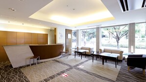 Een moderne hotel lobby met een receptiebalie, een zithoek en grote ramen met uitzicht op het omliggende landschap.