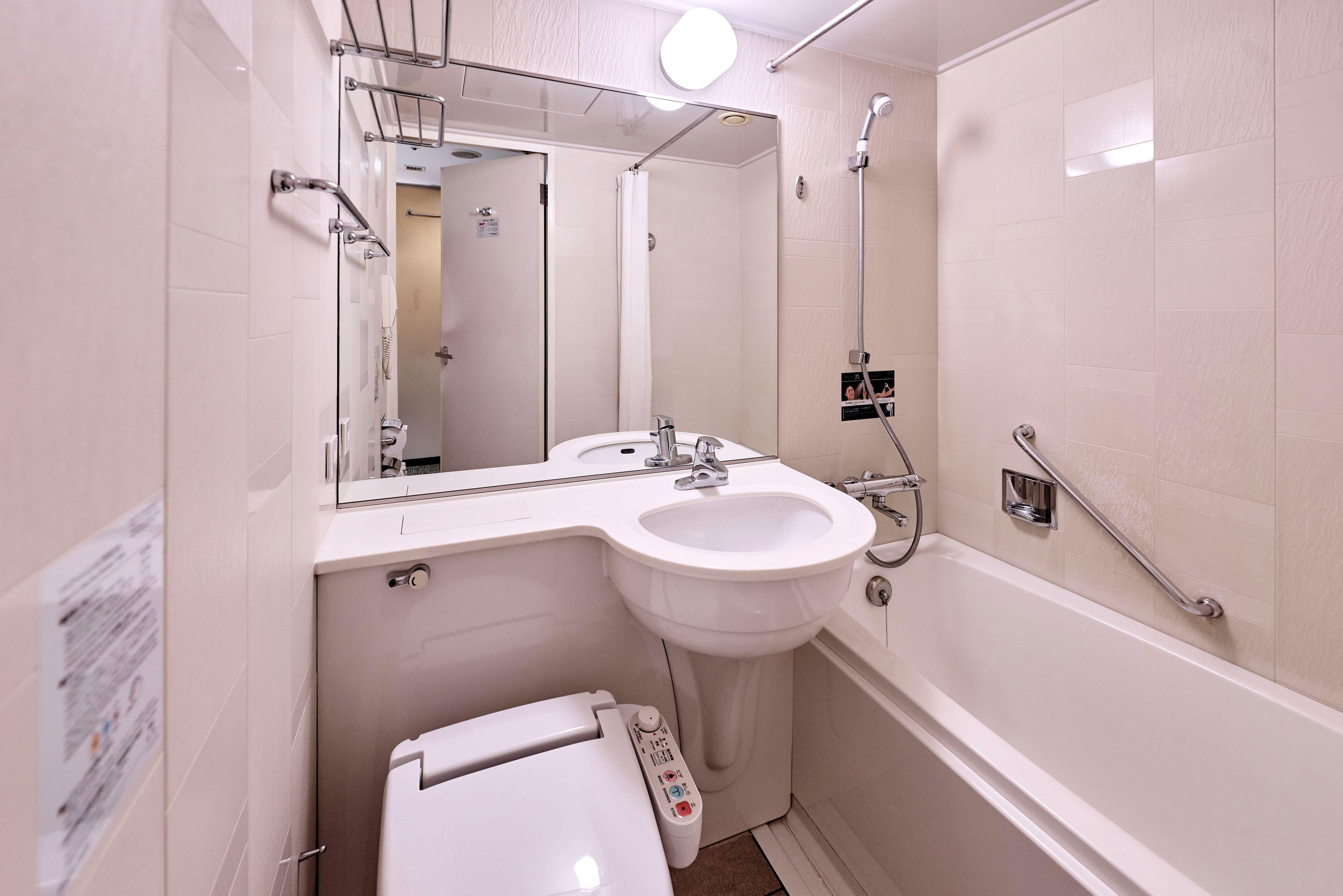 Une salle de bain avec un lavabo blanc, des toilettes, une douche et un miroir.