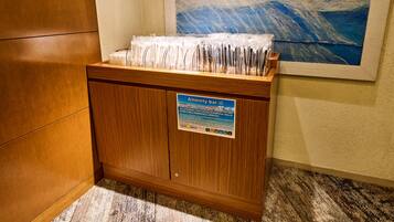 A hotel reception desk with a sign indicating amenities and a painting on the wall.