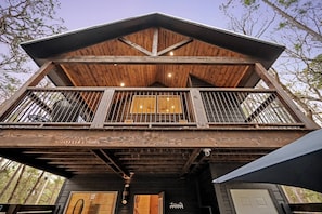 A wooden cabin with a balcony, a wooden deck, and a garage.