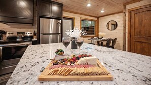 A kitchen with granite countertops, stainless steel appliances, and a wooden ceiling. - Cozy Modern Farmhouse Hot Tub, Firepit, Game Table (Broken Bow)