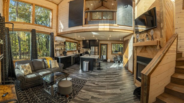 A spacious interior with a living area, kitchen, and a staircase leading to an upper level. - Cozy Modern Farmhouse Hot Tub, Firepit, Game Table (Broken Bow)