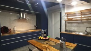 Una cocina moderna con armarios azules, encimera de madera, pileta de acero inoxidable y extractor de aire integrado.