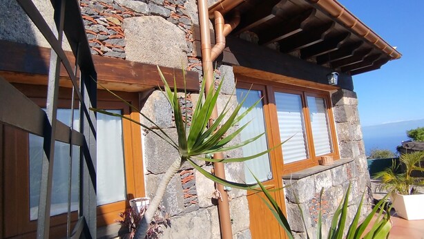 Un edificio de piedra con un balcón de madera, ventanas amplias y vistas al océano.