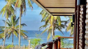Un balcon avec vue sur l’océan et les palmiers.
