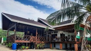 Un bâtiment à deux étages doté d’une terrasse en bois et d’un espace extérieur couvert.