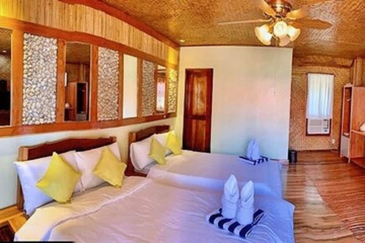 Une chambre d’hôtel avec deux lits, une télévision et un plafond en bois.