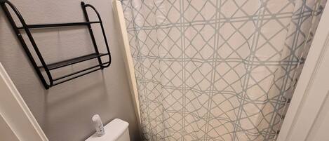 A small bathroom with a toilet, a shower curtain, and a towel rack.