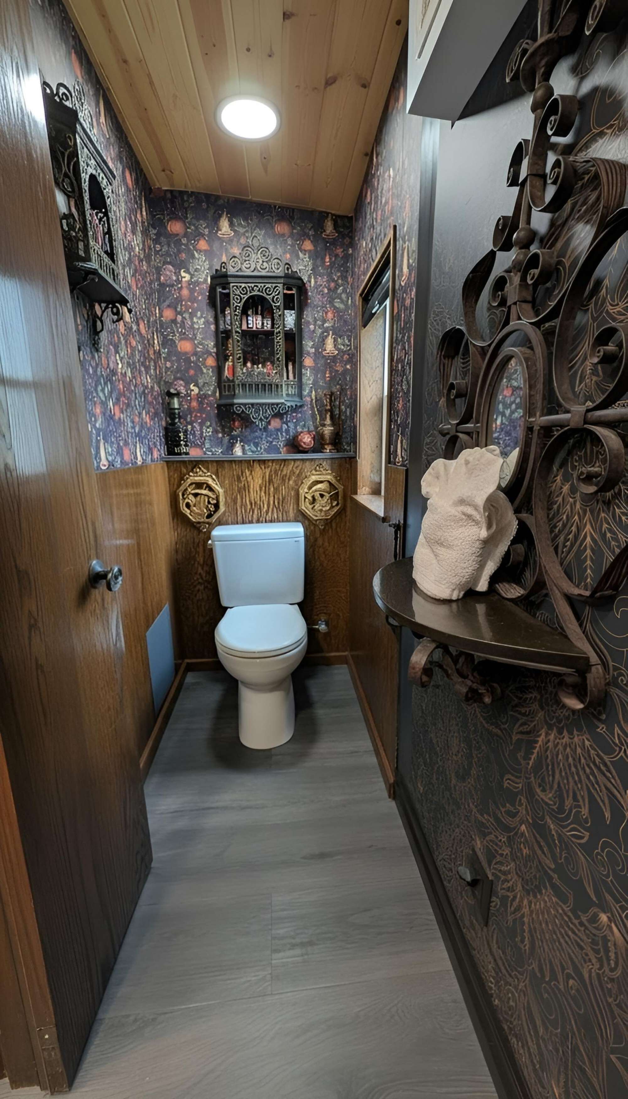 Un bagno stretto con il water, uno scaffale con un asciugamano e decorazioni elaborate alle pareti.