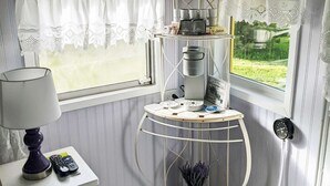 A room with a window, a table with a lamp, a shelf with kitchen items, and a sign reading 'LAVENDER'. - Lavender Limited at Olympic Railway Inn - Pet Friendly (Sequim)