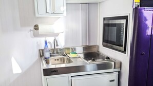 A compact kitchen with a sink, a microwave, and a refrigerator. - Lavender Limited at Olympic Railway Inn - Pet Friendly (Sequim)