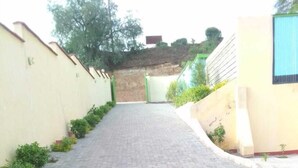 A paved pathway leading to a building with a green gate. - Mongare Lodge and restaurant (Narok)