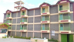 A multi-story building with balconies and a small adjacent structure. - Mongare Lodge and restaurant (Narok)