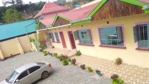 A two-story building with a tiled driveway and a parked car. - Mongare Lodge and restaurant (Narok)