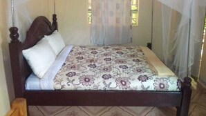 A bed with a floral bedspread, a white pillow, and a canopy. - Mongare Lodge and restaurant (Narok)