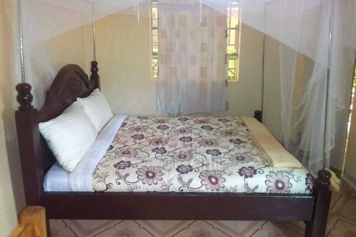 Ein Bett mit einer blumigen Tagesdecke, einem weißen Kopfkissen und einem Baldachin.