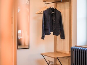 Une pièce avec un radiateur en bois, une table en bois et une veste noire suspendue à un cintre.