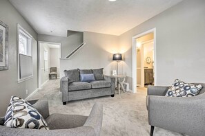 Relax in this stylish living room with a grey sofa, armchair, and side table, featuring a lamp and framed artwork.