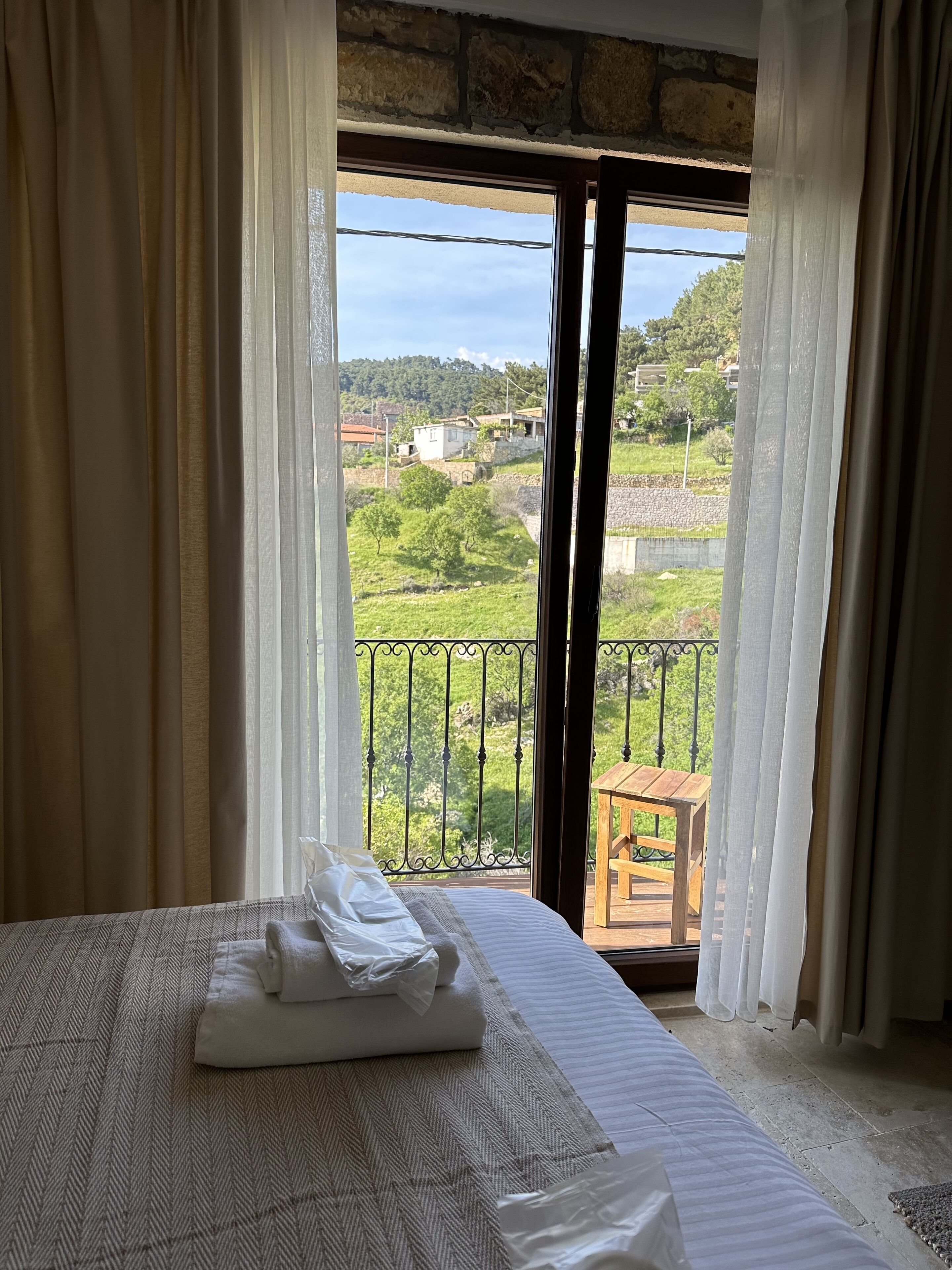 Une chambre d’hôtel avec un lit, une table en bois et un balcon donnant sur la campagne.
