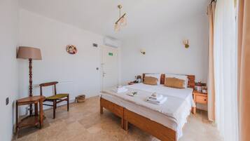A bedroom with a large bed, a wooden chair, a bedside table, and a lamp.