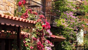 A stone building with balconies, a garden with pink flowers, and outdoor seating. - Arıklı Han Kazdağları (Ayvacik)