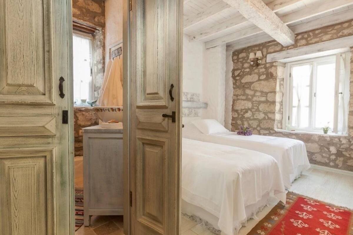 Une chambre avec deux lits, un mur en pierre et un plafond en bois.
