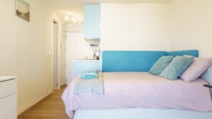 Un dormitorio con cama, mesita de noche y un escritorio pequeño con lámpara.
