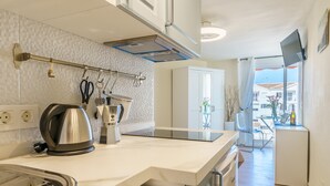 Una cocina moderna con horno empotrado, hervidor y cafetera. Se ve una ventana con vistas al exterior.