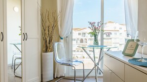 Una habitación moderna con una mesa de vidrio, una silla, un florero con flores y un cuadro en la pared.