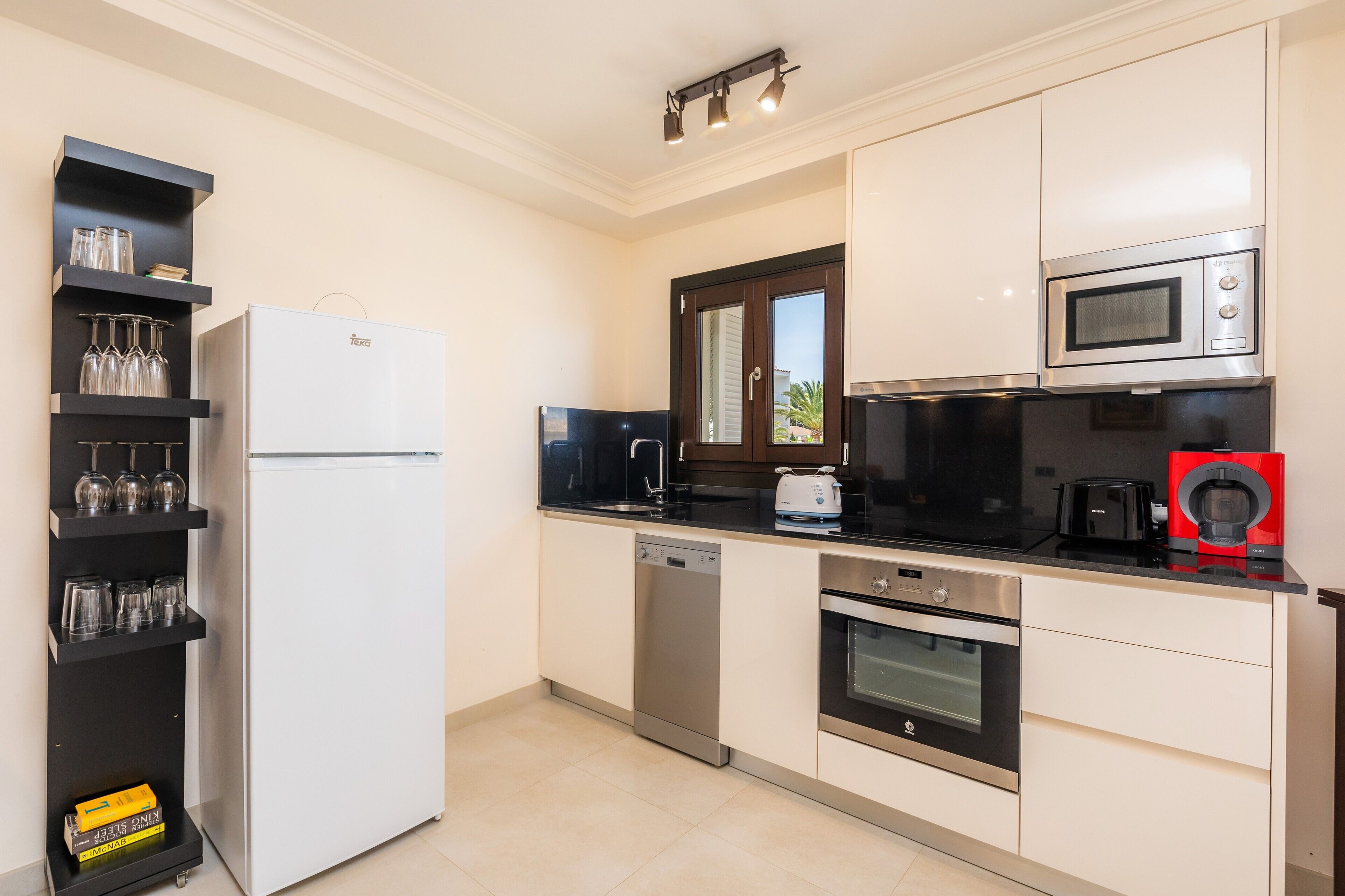 A modern kitchen with a refrigerator, microwave, toaster, and dishwasher.
