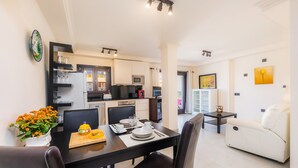 A modern kitchen with white cabinets, a dining table set with plates, glasses, and a vase of flowers.