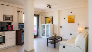 A modern living room with a sofa, a coffee table, and a kitchen area with appliances.
