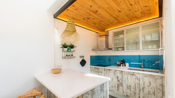 A kitchen with a white island, wooden ceiling, and blue backsplash. - Country House 'Finca Es Canyaret' with Mountain View, Pool & Garden (Capdepera)