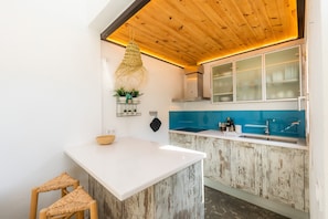 Een keuken met een wit eiland, houten plafond en blauwe spatwand.