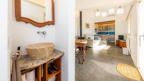 A bathroom with a large bowl sink, a wooden vanity, a mirror, and a towel rack. The image also shows a dining area with a table, chairs, and a rug. - Country House 'Finca Es Canyaret' with Mountain View, Pool & Garden (Capdepera)