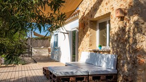 A wooden deck with a bench, a potted plant, and a stone wall. - Country House 'Finca Es Canyaret' with Mountain View, Pool & Garden (Capdepera)