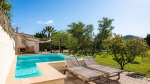 A swimming pool with lounge chairs, a barbecue area, and a view of a green landscape. - Country House 'Finca Es Canyaret' with Mountain View, Pool & Garden (Capdepera)