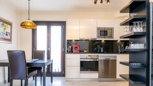 Une cuisine moderne avec des armoires blanches, des appareils en acier inoxydable et un coin repas comprenant une table et des chaises.